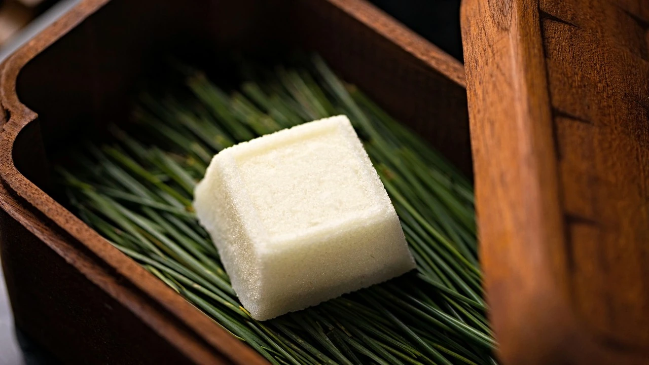Un dolce wagashi bianco su aghi di pino freschi, dentro una scatola di legno